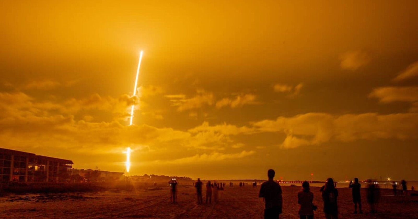 Rocket launch rising above spectators on a beach